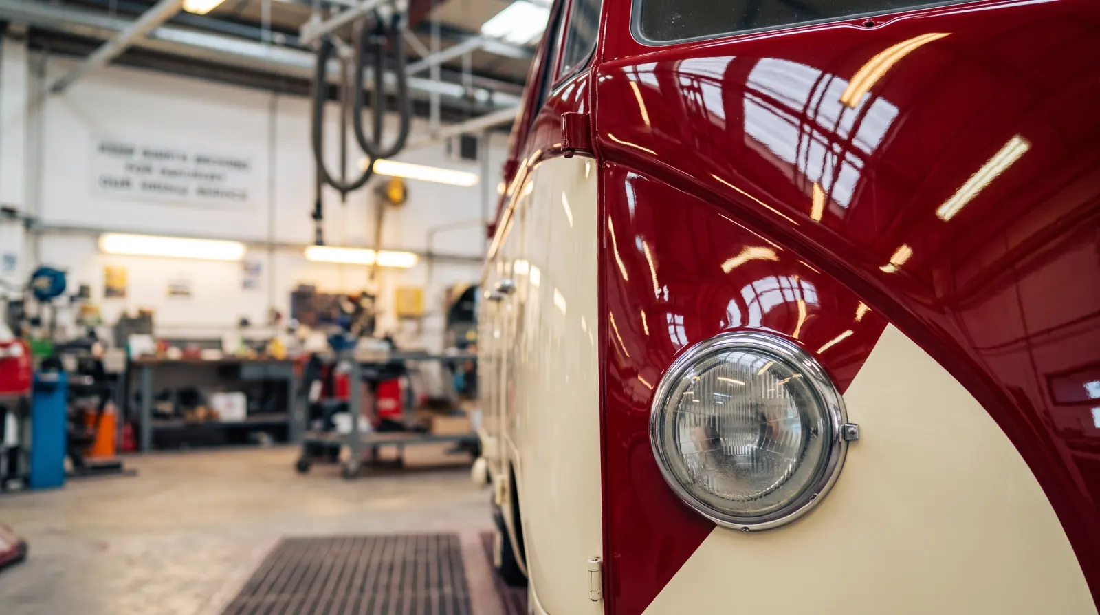 The finished red and cream two-tone on the front of a VW camper, the red coming down to a point beside the headlight