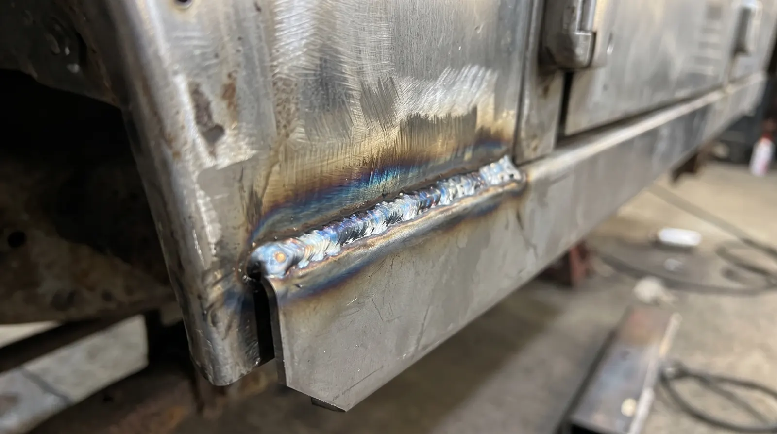 A new strip of steel seam welded along the bottom of a Land Rover panel, the weld still coloured from the heat