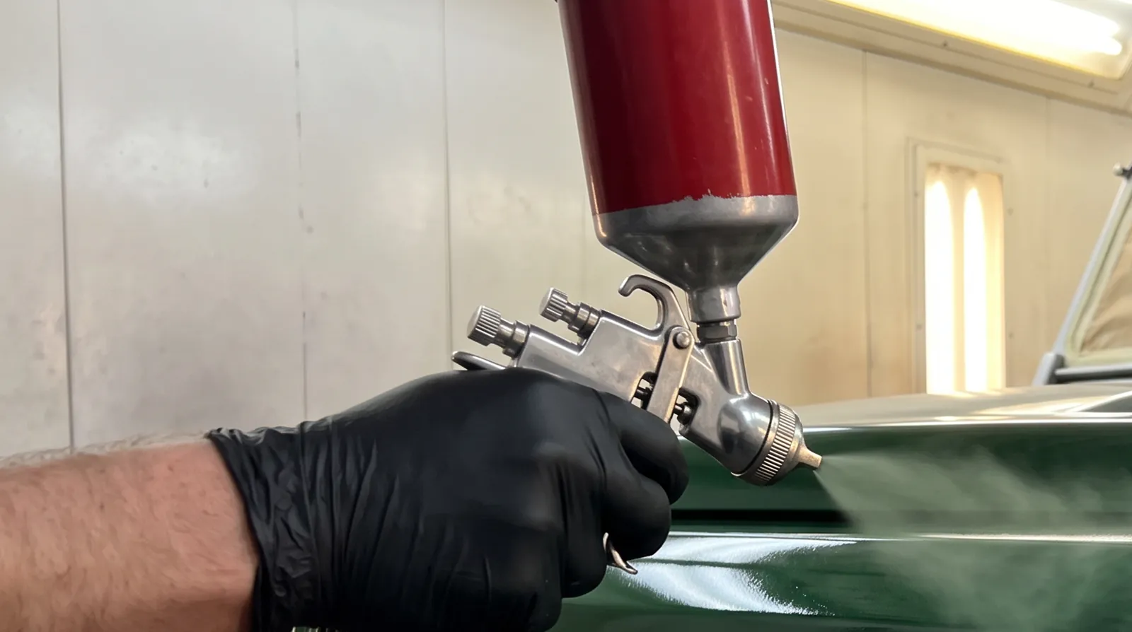 Green paint going on the wing of a Land Rover Defender in the spray booth