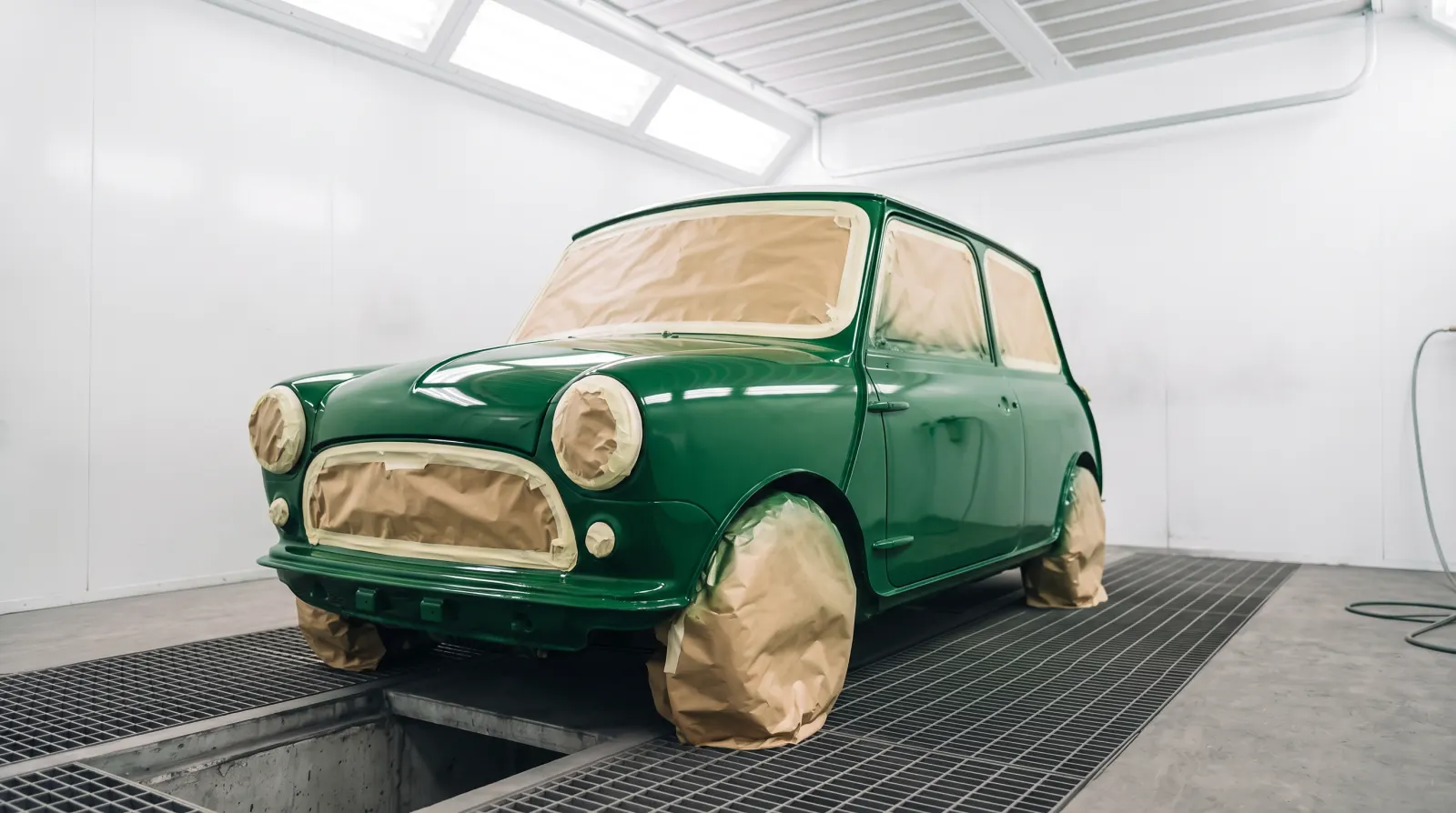 A classic Mini in its new green, masked up in the spray booth