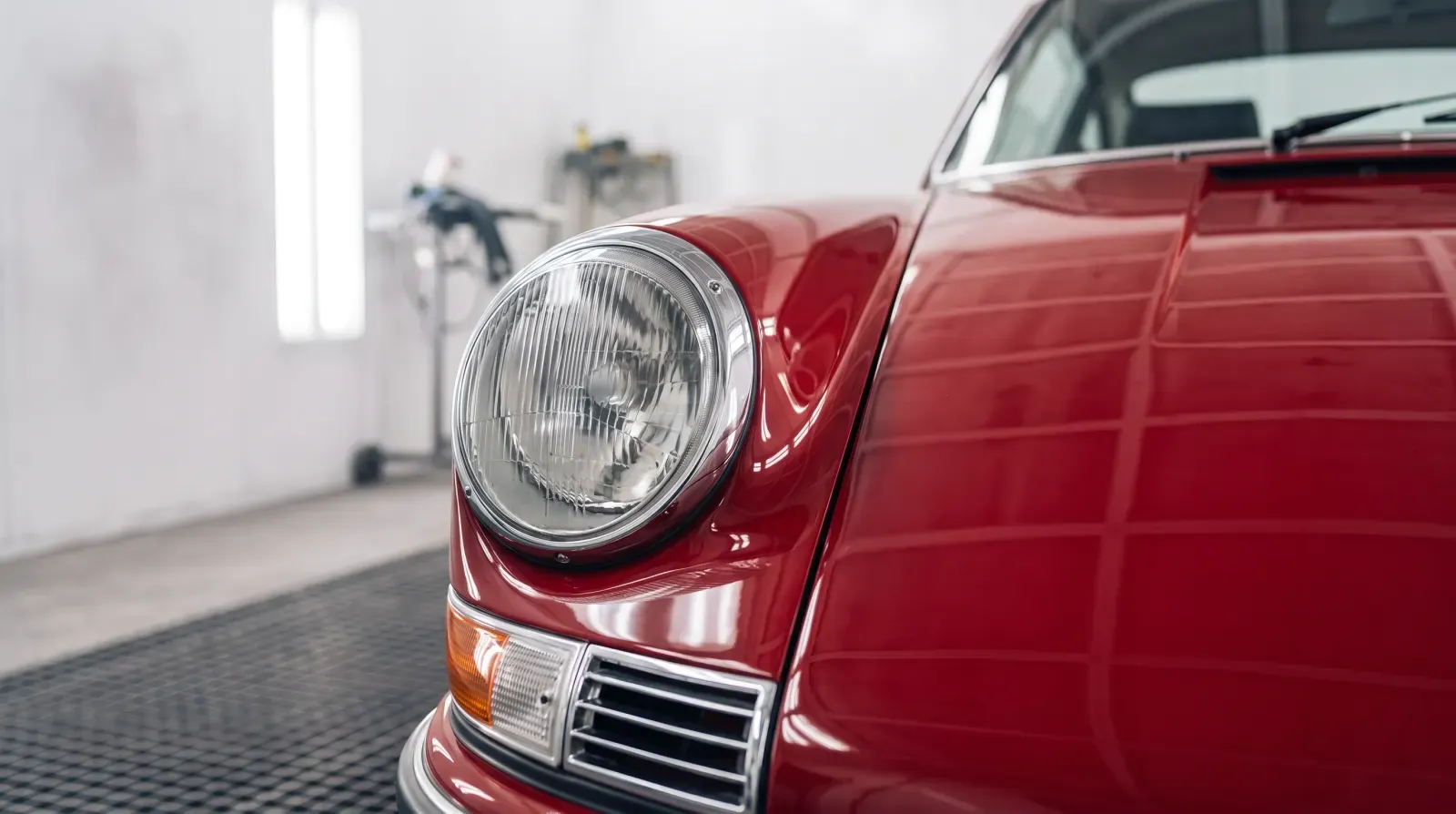 Fresh red gloss on the wing and headlight of a classic 911, still in the spray booth