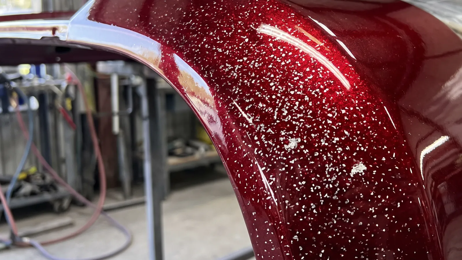 Metal flake sparkling in deep red paint on a curved wing