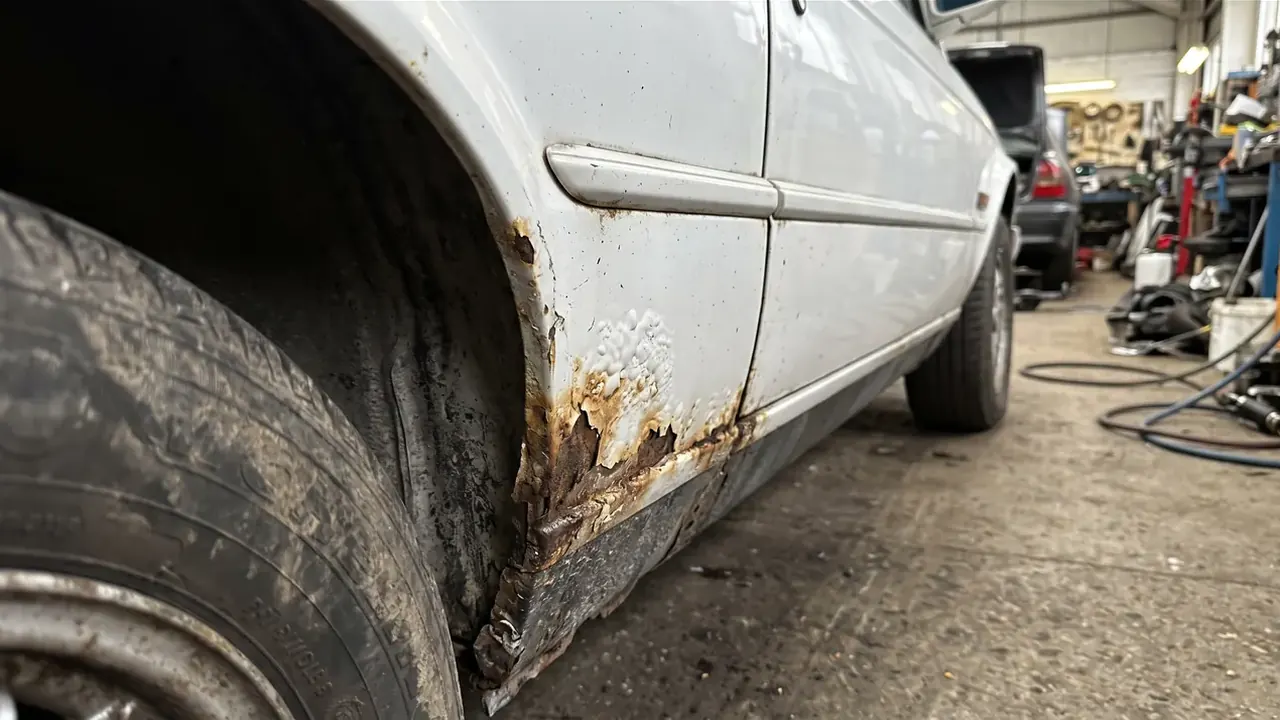 Rust bubbling round the rear wheel arch of a white classic