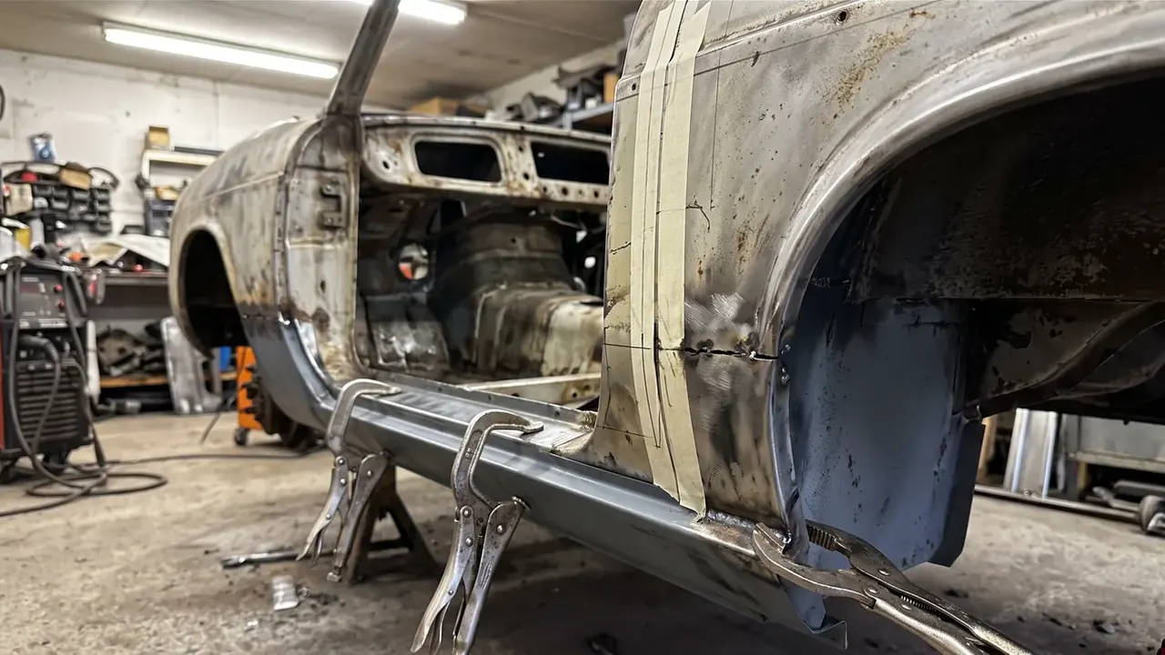 A new sill clamped in place along a classic shell before welding