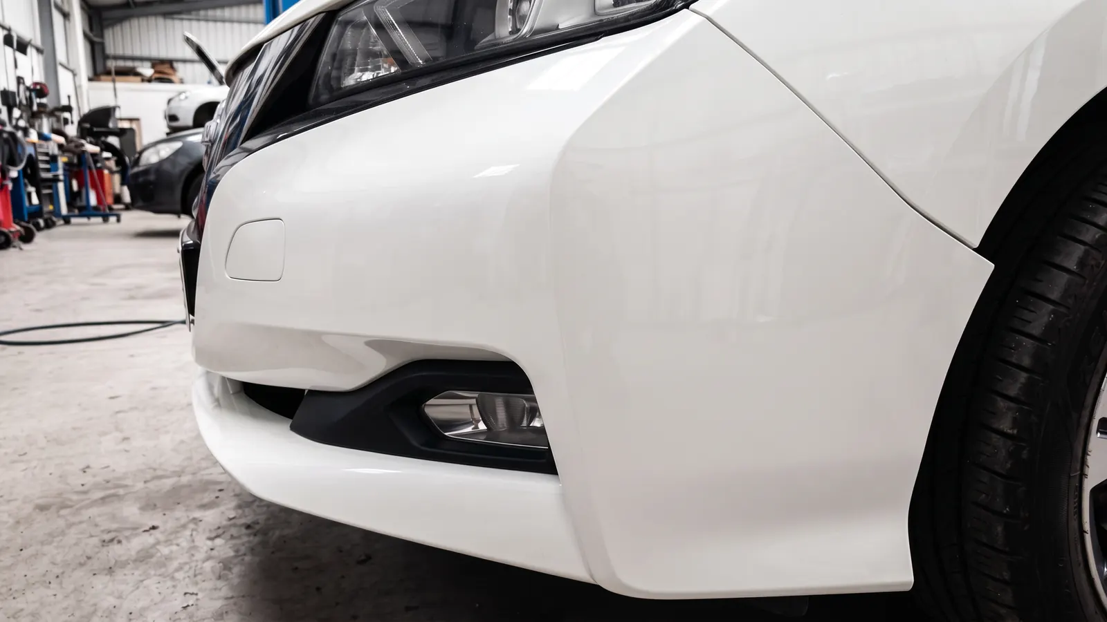 The same white bumper corner, scuffed and cracked before and smooth and painted after, after