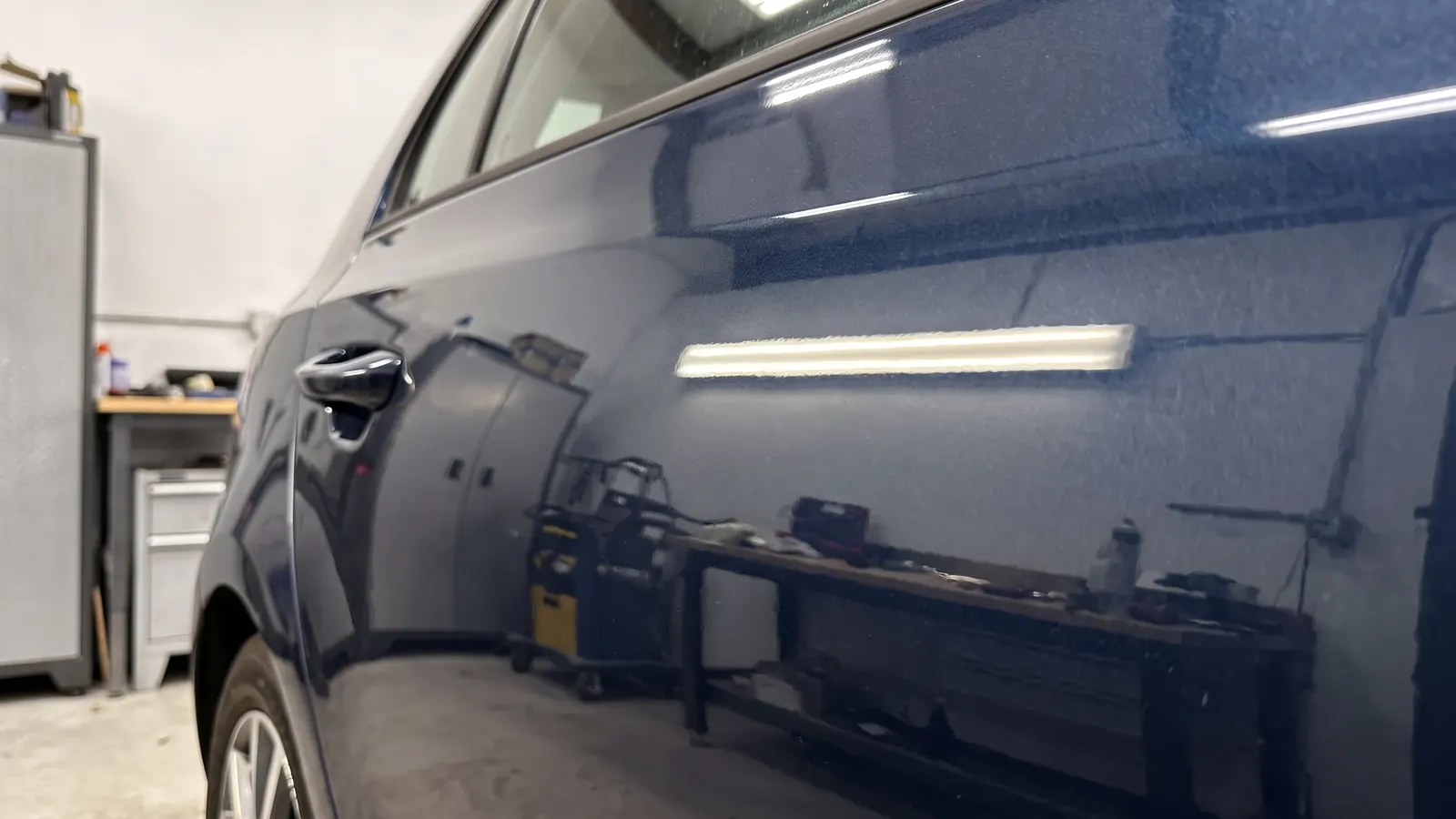 A dent in a dark blue rear door, after