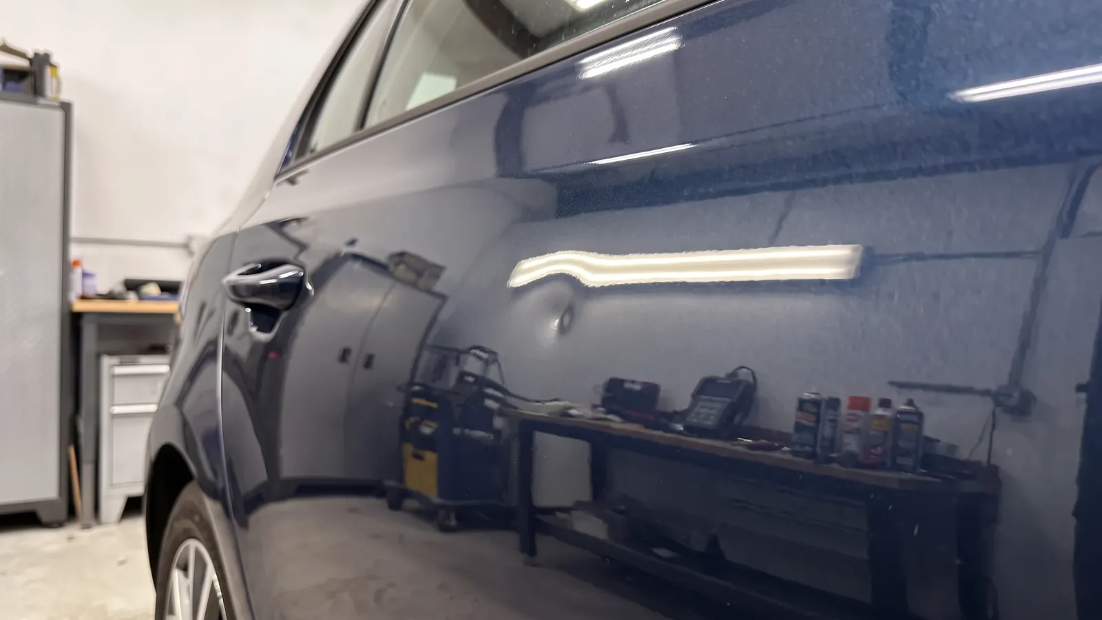 A dent in a dark blue rear door, before