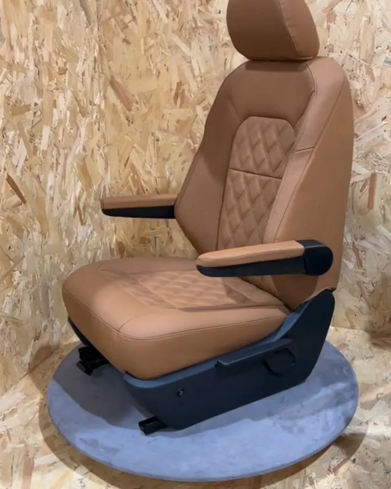 A tan leather seat with armrests and diamond stitching on a turntable in the workshop