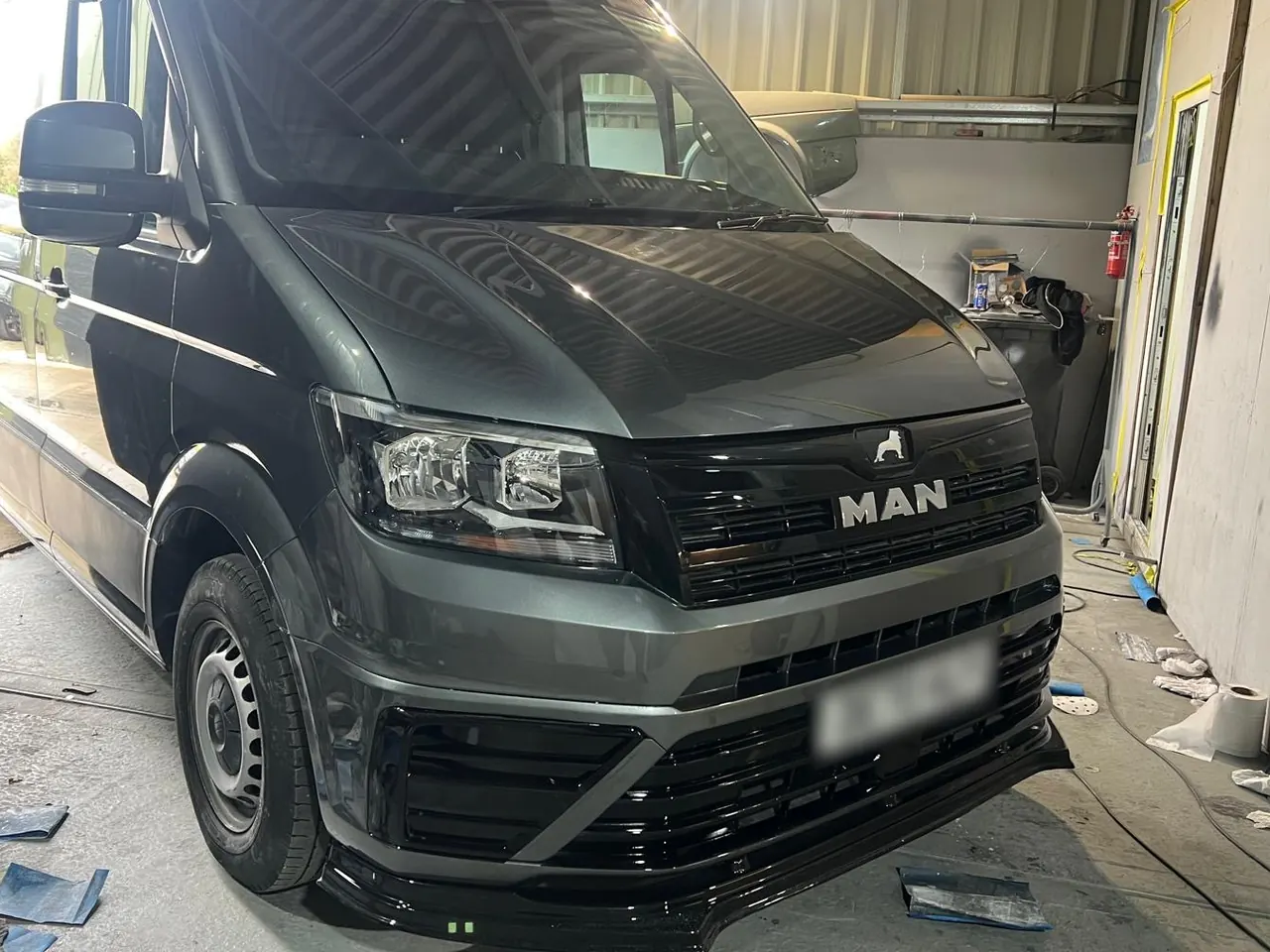 A large MAN van in grey under the shop lights
